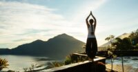 Kobieta ćwicząca jogę na tarasie z widokiem na egzotyczne morze i górę na Bali