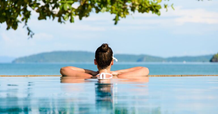 Relaks i spa. Kobieta z kwiatem we włosach relaksuje się w basenie z widokiem na morze w Krabi, Tajlandia