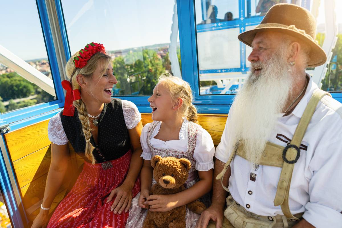 na zdjęciu trzyosobowa rodzina w wagoniku kolejki, dziewczynka trzyma na kolanach pluszowego misia