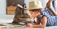 funny happy child girl tourist with world map, backpack and magnifier