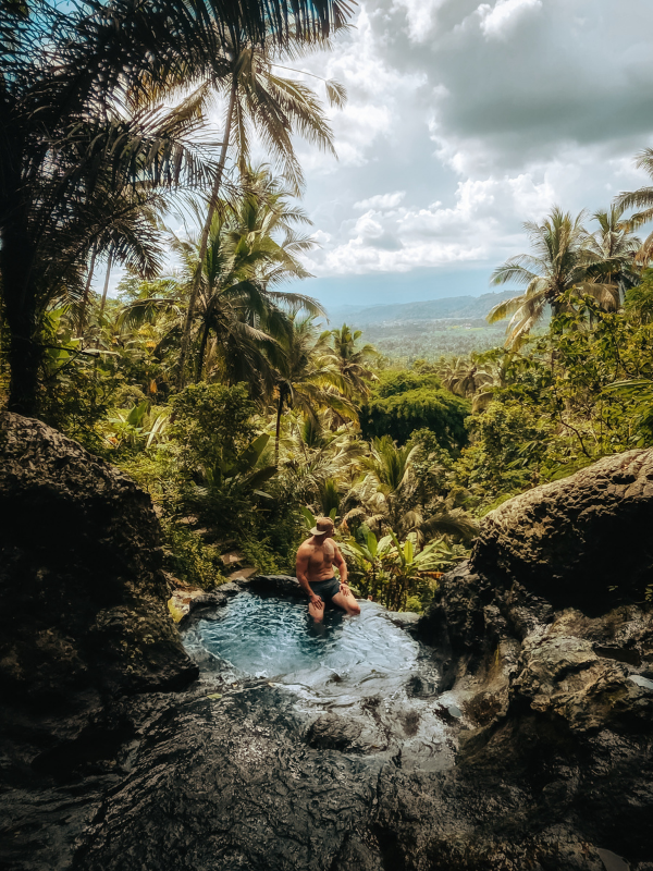 Naturalny basen przy wodospadzie na Bali w Indonezji, turysta kąpiący się wśród tropikalnej dżungli i palm Paweł Mazur