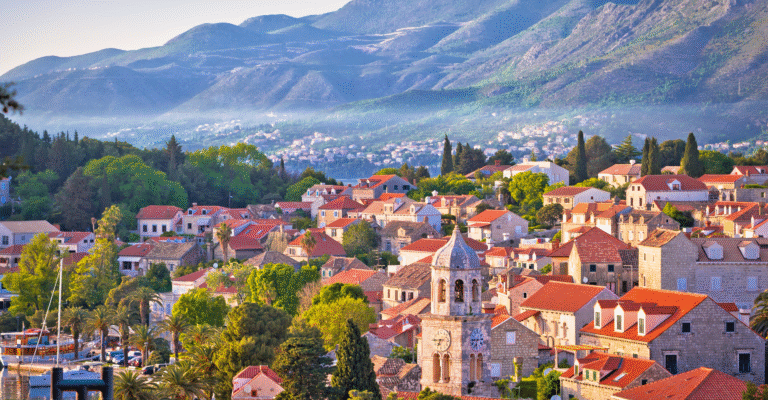 Malowniczy widok na Cavtat w Chorwacji z czerwonymi dachami domów i górami w tle, popularna destynacja turystyczna nad Adriatykiem.