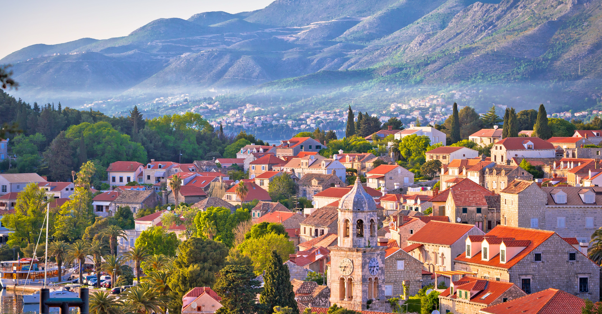 Malowniczy widok na Cavtat w Chorwacji z czerwonymi dachami domów i górami w tle, popularna destynacja turystyczna nad Adriatykiem.