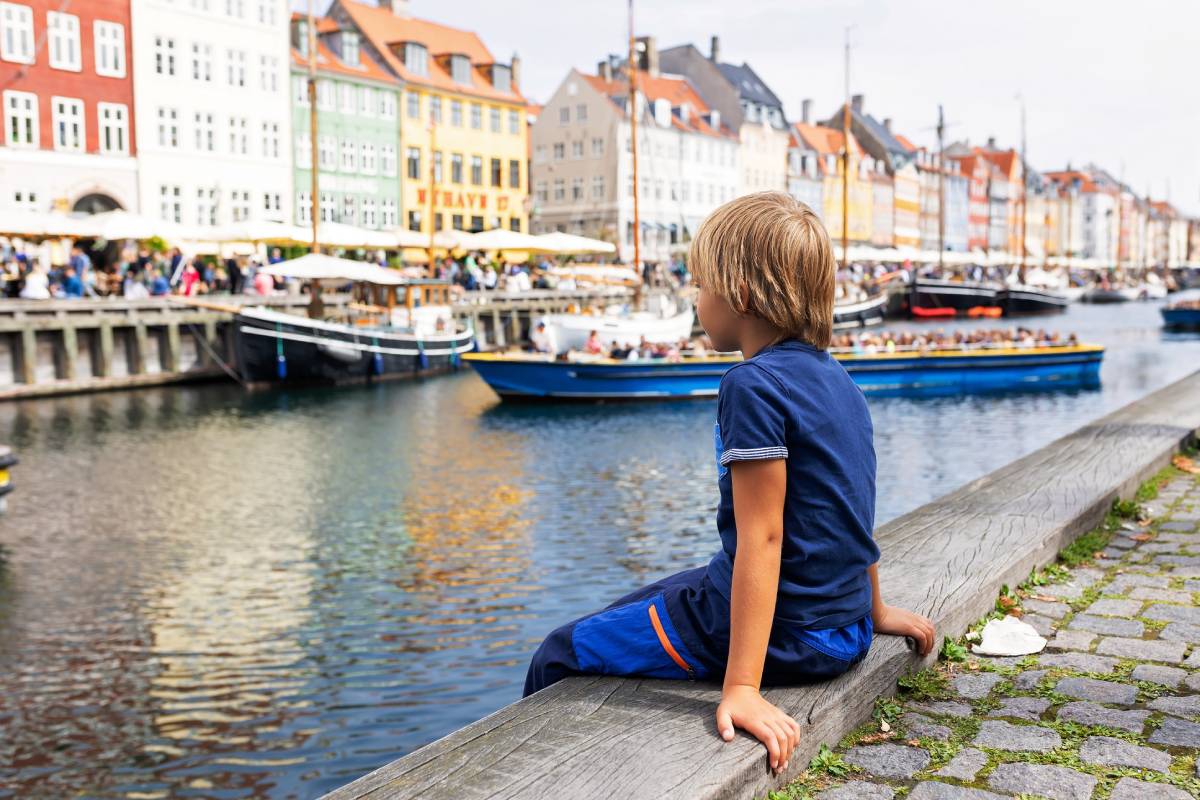 Chłopiec siedzący na nabrzezu w dzielnicy Nyhavn w Kopenhadze © Shutterstock