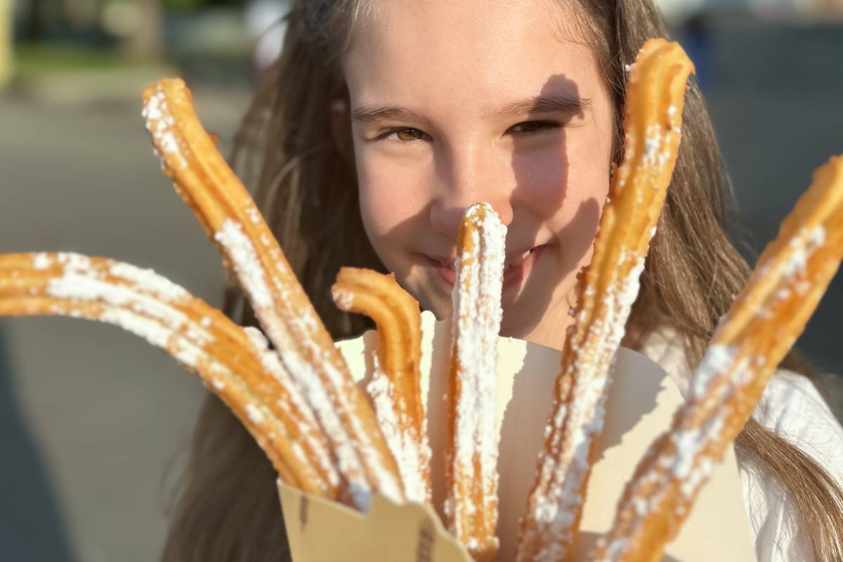 Dziewczynka jedząca tradycyjne hiszpańskie churros © Shutterstock
