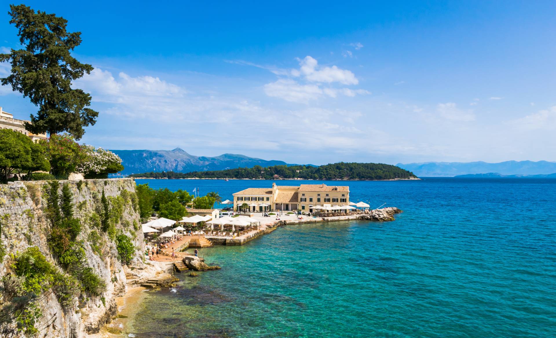 Faliraki na Korfu z łaźniami publicznymi i plażą z wysepką Vido w tle na wyspie Korfu, Grecja © Shutterstock