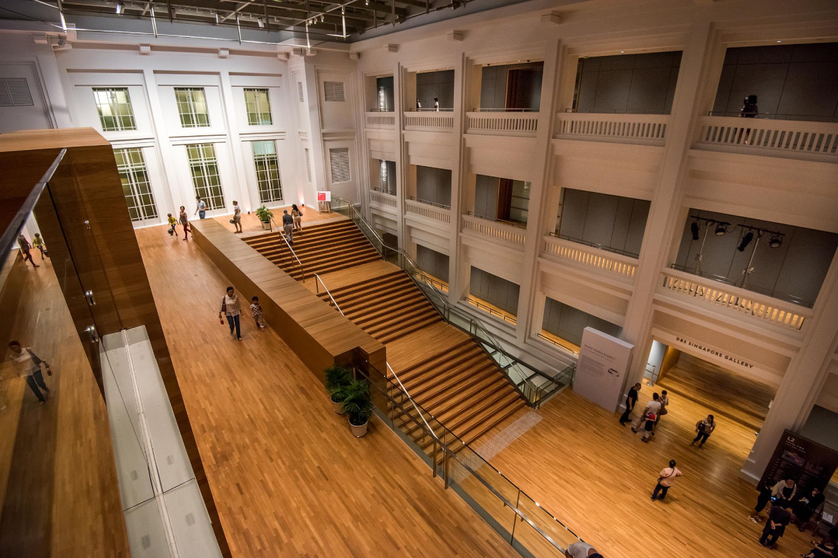 Galeria Atrium Drewniane schody Chodzenie, Galeria Narodowa w Singapurze
Wnętrze Galerii Narodowej w Singapurze przedstawia wielopoziomową przestrzeń z drewnianymi podłogami i schodami. Widoczne są osoby chodzące po podłogach i schodach. Budynek posiada duże okna i wielopoziomowe atrium z balkonami. Architektura jest nowoczesna i przestronna, a naturalne światło oświetla całą scenę.
