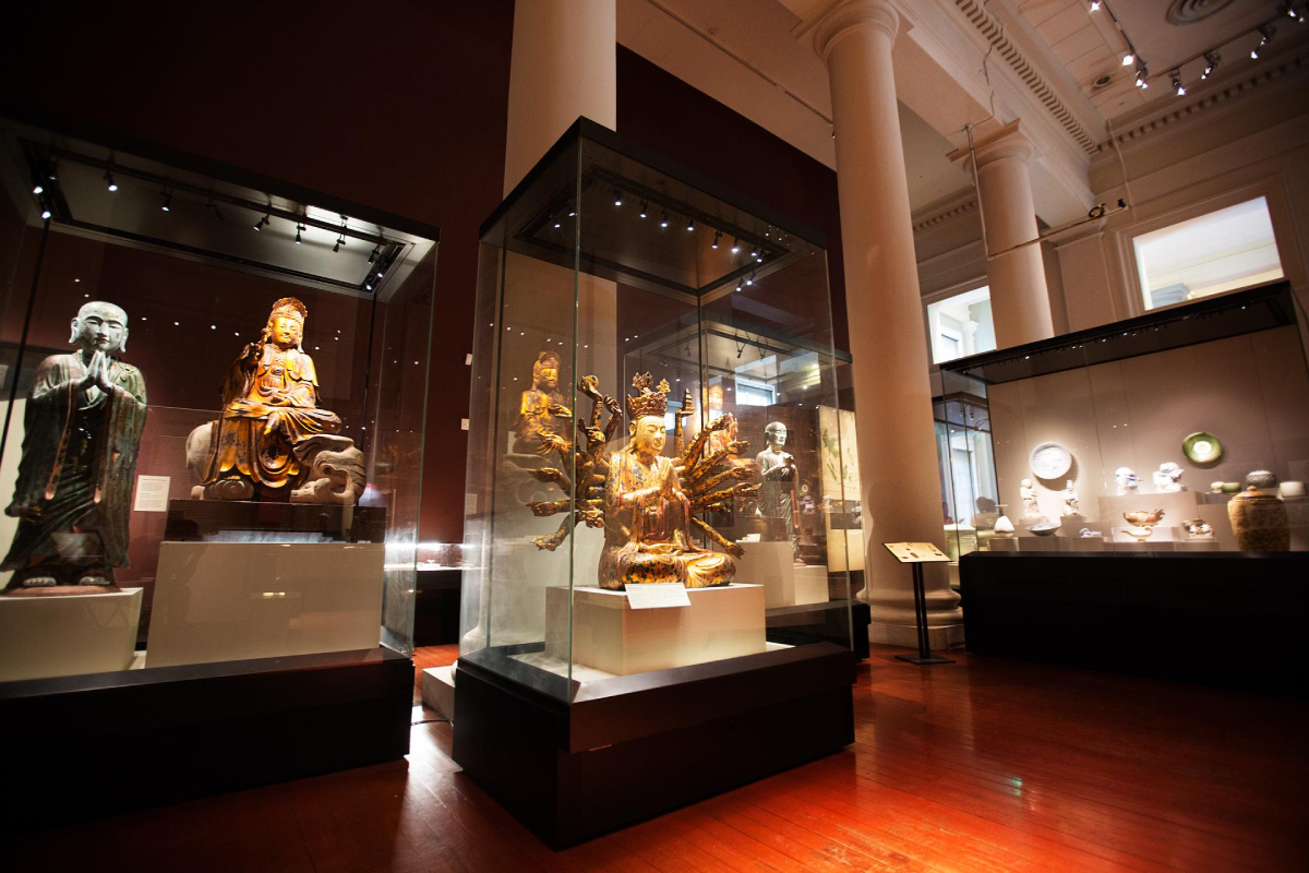 Złote posągi religijne w szklanych gablotach, Muzeum Cywilizacji Azjatyckich
Wnętrze muzeum eksponuje różne złote posągi w szklanych gablotach. Posągi przedstawiają postacie religijne, a muzeum ma wypolerowaną drewnianą podłogę. Oświetlenie jest przytłumione, a eksponaty oświetlają reflektory punktowe.