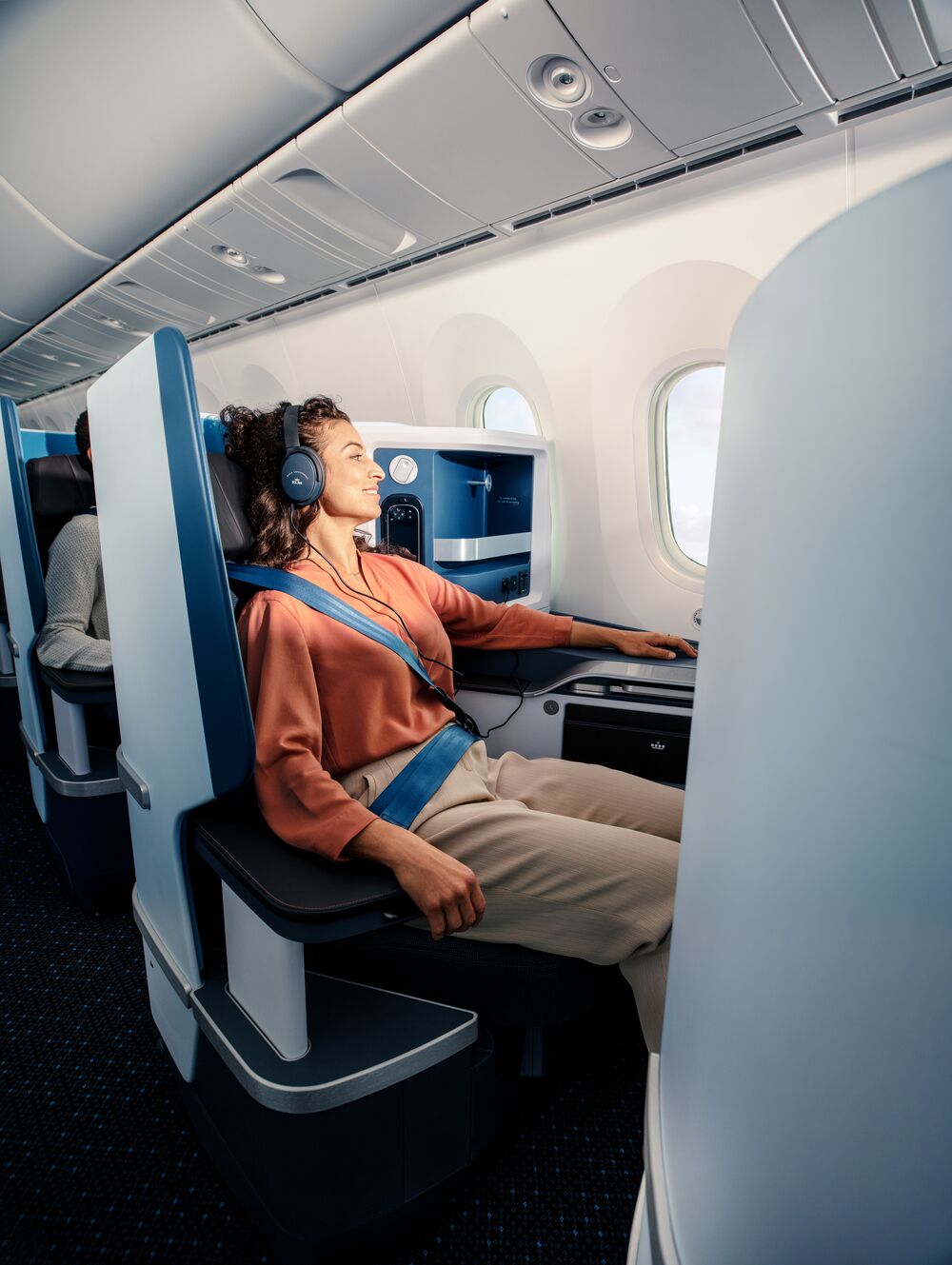 Relaks w klasie biznes linii KLM – pasażerka wygodnie odpoczywa na rozkładanym fotelu w nowoczesnej kabinie samolotu. Więcej przestrzeni, luksusowe udogodnienia i wyjątkowy komfort podróży. Odkryj korzyści klasy biznes KLM i podróżuj w najwyższym standardzie