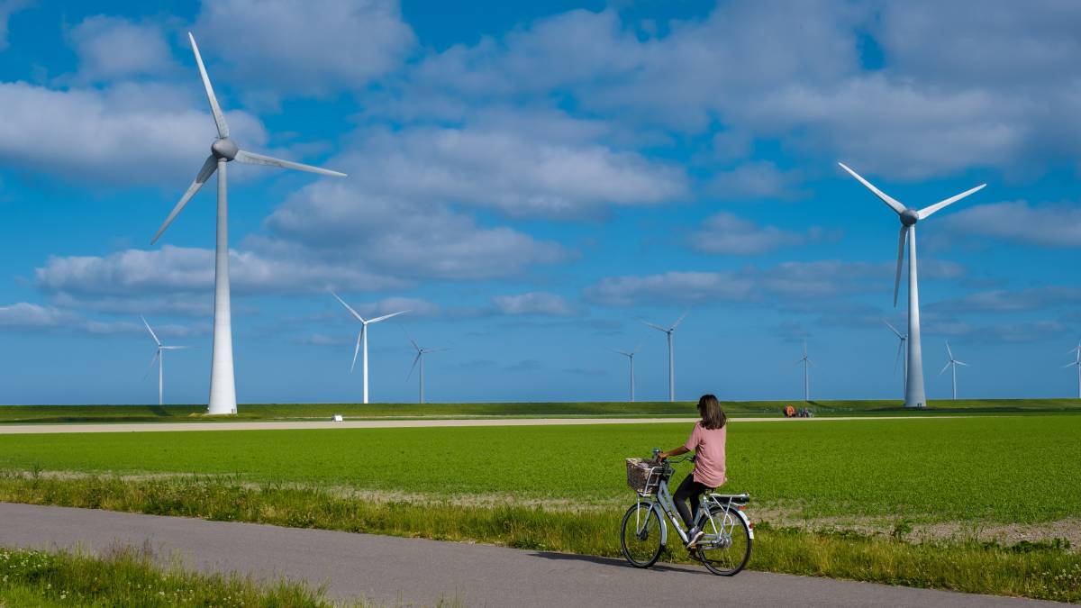 Młoda kobieta na zielonym rowerze elektrycznym na tle farmy wiatrowej w Holandii © Shutterstock