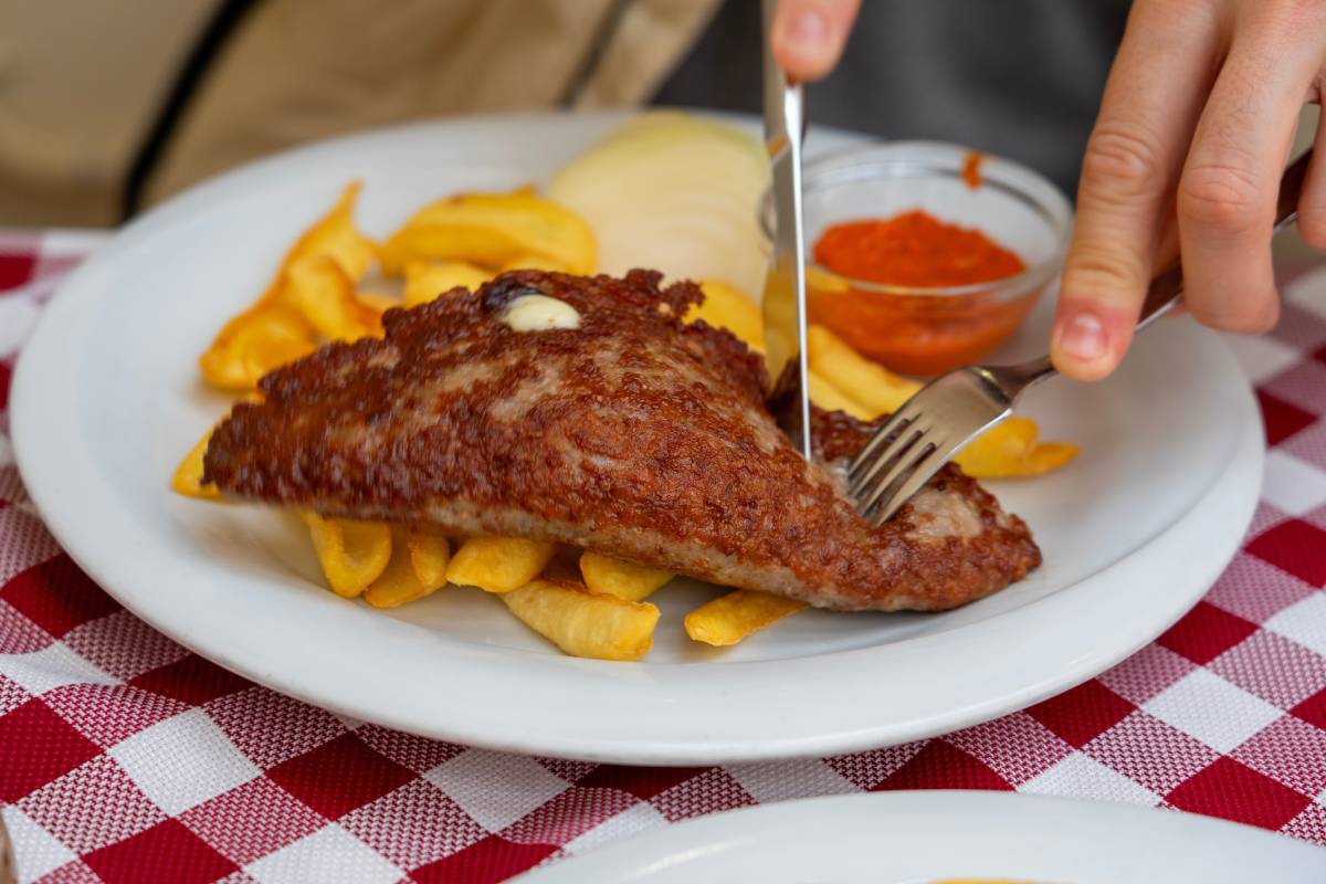 Pljeskavica nadziewana serem – popularne bałkańskie danie wieprzowe na talerzu z ajvarem i frytkami © Shutterstock