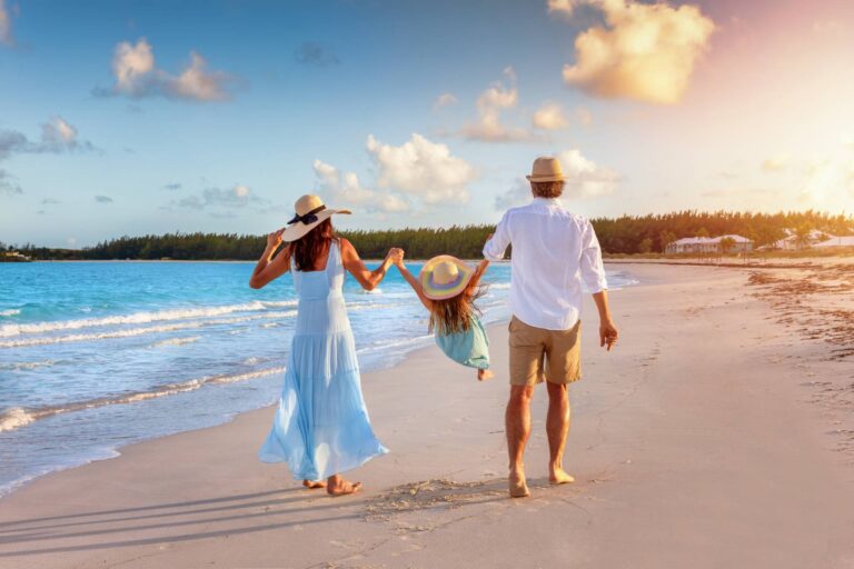 Szczęśliwa rodzina spaceruje ręka w rękę po tropikalnej plaży o zachodzie słońca i cieszy się letnim czasem wakacji © Shutterstock