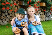 Szczęśliwe dzieci w tradycyjnych bawarskich strojach jedzą precle © Shutterstock