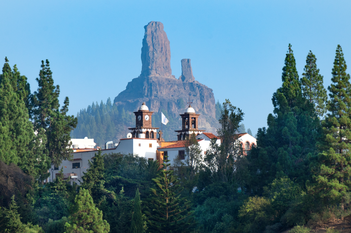 Widok na kościół w Tejeda otoczony sosnami kanaryjskimi, z charakterystyczną skałą Roque Nublo w tle, Gran Canaria.