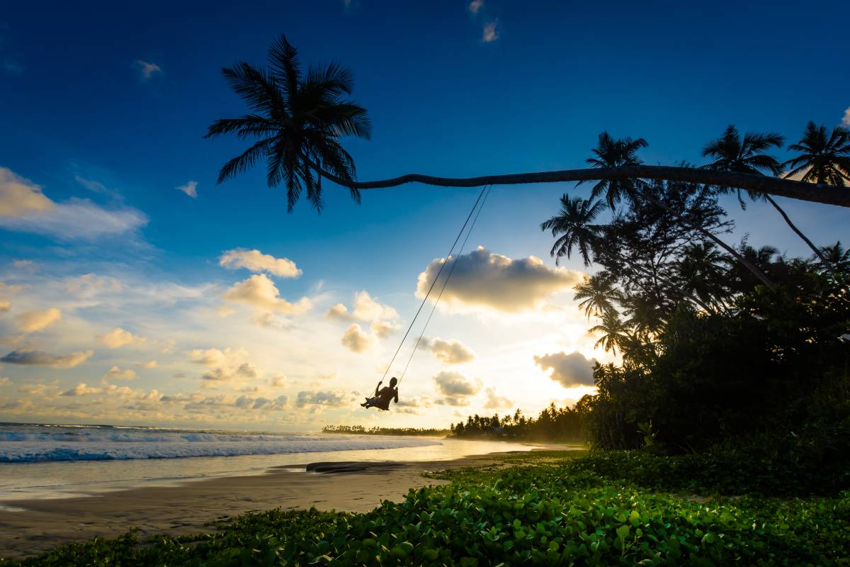 Turystka podziwia zachód słońca na huśtawce palmowej na Sri Lance, Dalawella Beach © Shutterstock