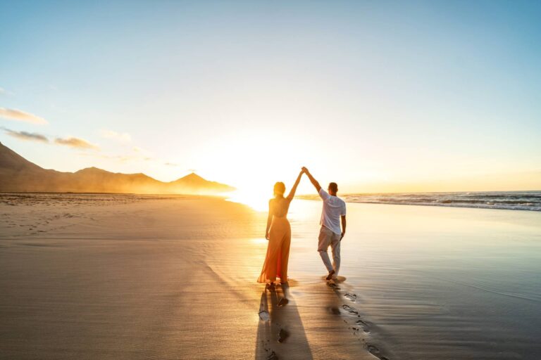 Urocza, romantyczna para spacerująca po plaży o zachodzie słońca © Shutterstock