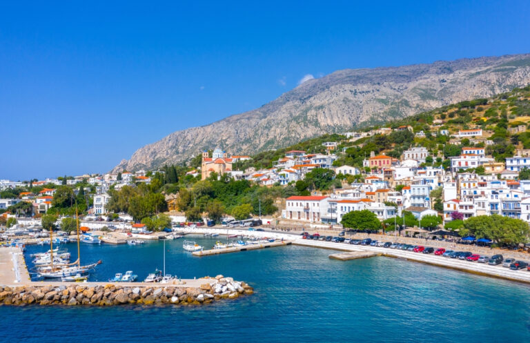 Agios Kirikos – stolica wyspy Ikaria w Grecji, widok na port, białe domy z czerwonymi dachami i górzyste krajobrazy nad Morzem Egejskim, popularny kierunek wakacyjny w archipelagu Wysp Egejskich. Blue Zone