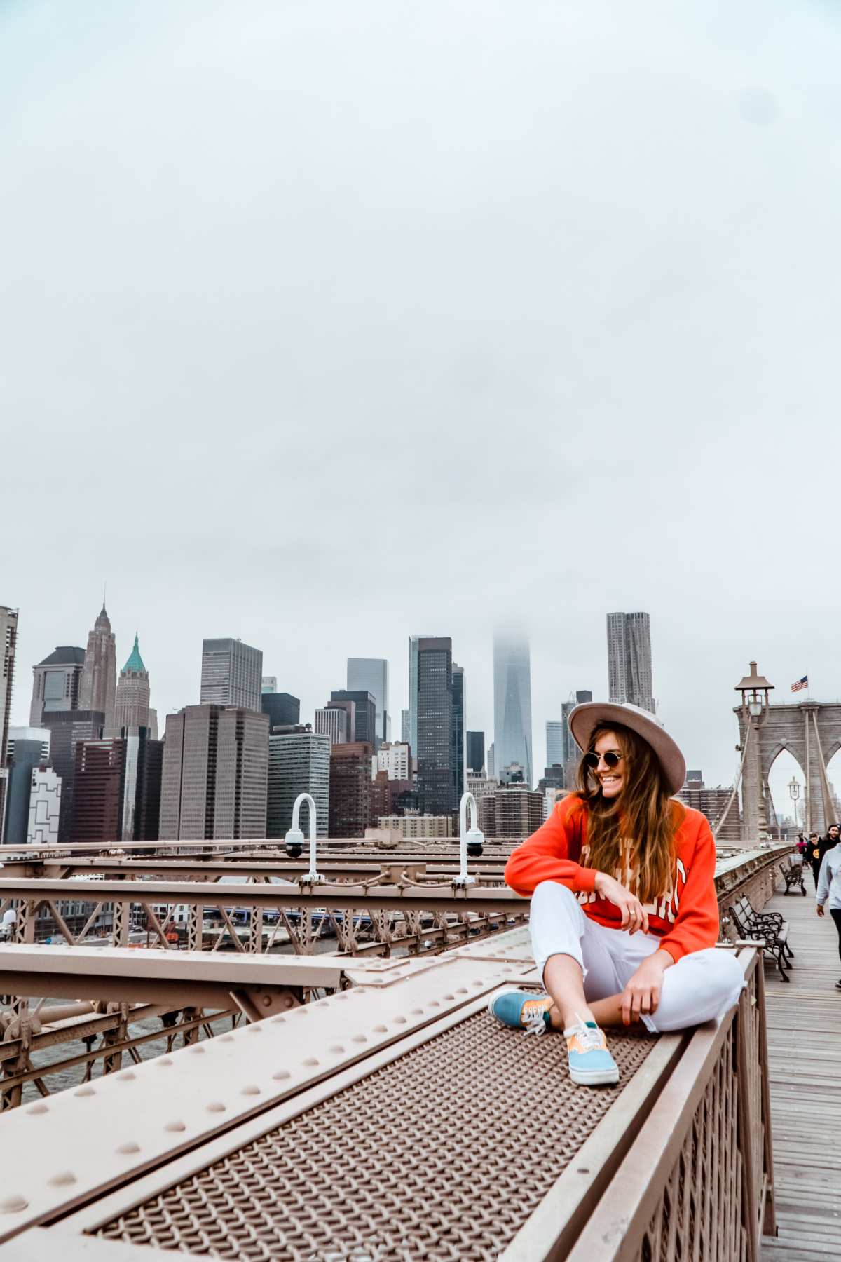 Ewelina Tomkiewicz stewardesa na Moście Brooklińskim w Nowym Jorku z widokiem na panoramę Manhattanu i nowojorskie drapacze chmur w tle.