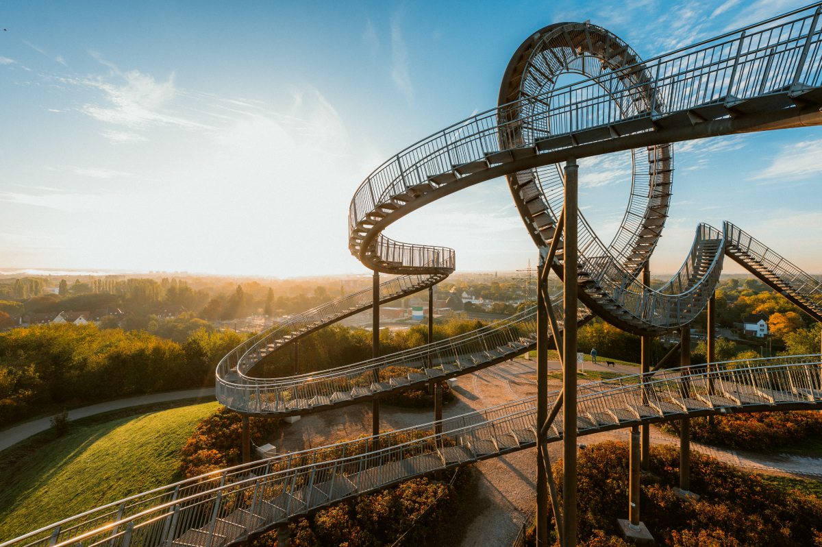 Instalacja artystyczna "Tiger and Turtle – Magic Mountain" w Duisburgu, przypominająca kolejkę górską. Na zdjęciu widać zakręcone, metalowe schody i platformy, które umożliwiają podziwianie panoramy okolicy, szczególnie podczas wschodu lub zachodu słońca.