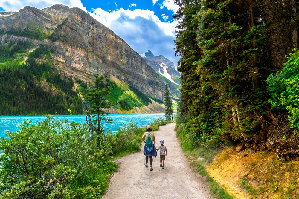 Matka z dzieckiem spacerująca szlakiem wzdłuż turkusowego jeziora Louise w Parku Narodowym Banff w kanadyjskich Górach Skalistych