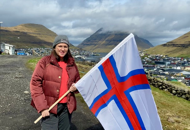 Kinga Eysturland z farerską flagą Merkið na tle miasta Klaksvík na Wyspach Owczych