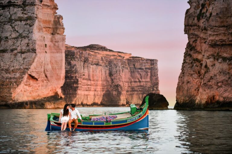 Para podczas romantycznego rejsu tradycyjną maltańską łodzią luzzu w Dwejra Bay na Gozo, Malta, o zachodzie słońca.