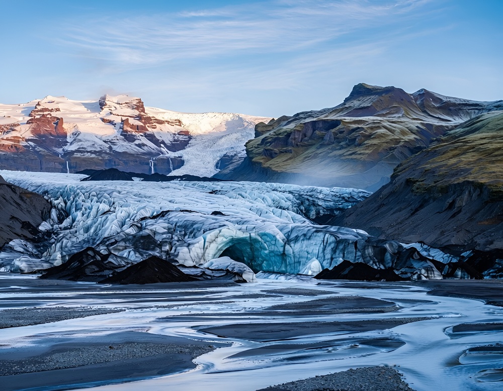 Lodowiec Vatnajökull i wijące się strumienie wody roztopowej na czarnych osadach wulkanicznych w Parku Narodowym Vatnajökull na Islandii