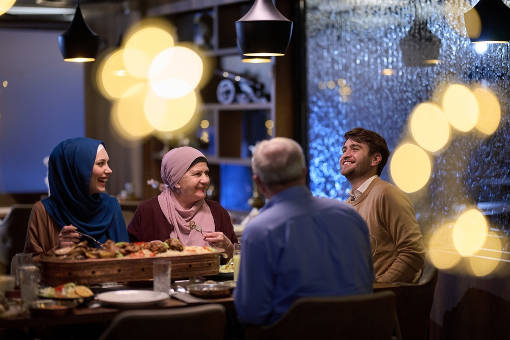 Rodzina muzułmańska spędzająca wspólny iftar w restauracji podczas Ramadanu, przy suto zastawionym stole i ciepłej, nastrojowej atmosferze.