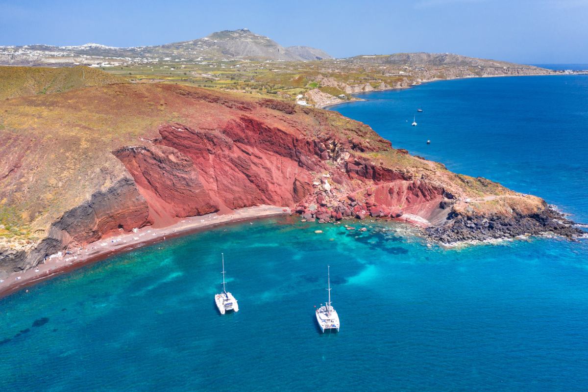 Niesamowite czerwone formacje na wybrzeżu Santorini widoczne z lotu ptaka