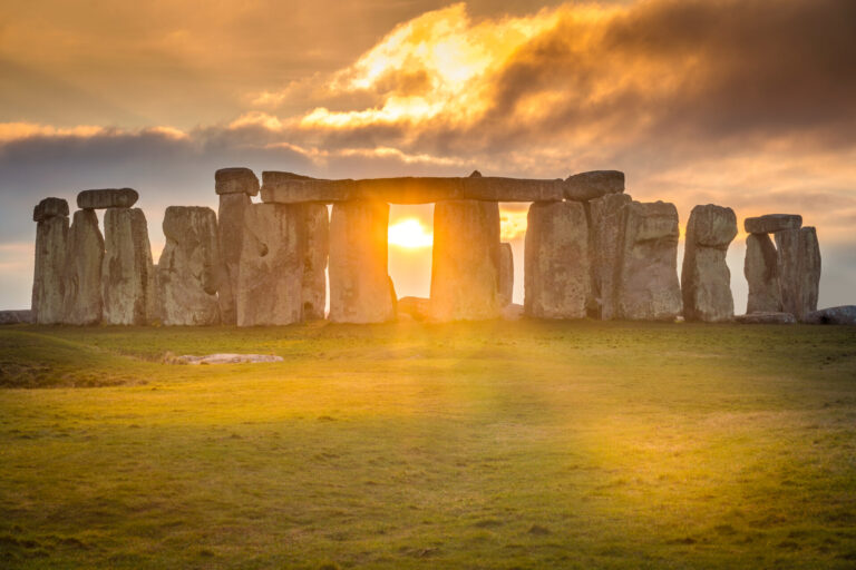 Stonehenge o zachodzie słońca – promienie światła przebijają się między kamiennymi blokami, tworząc niezwykły, tajemniczy klimat tego słynnego zabytku w Anglii.