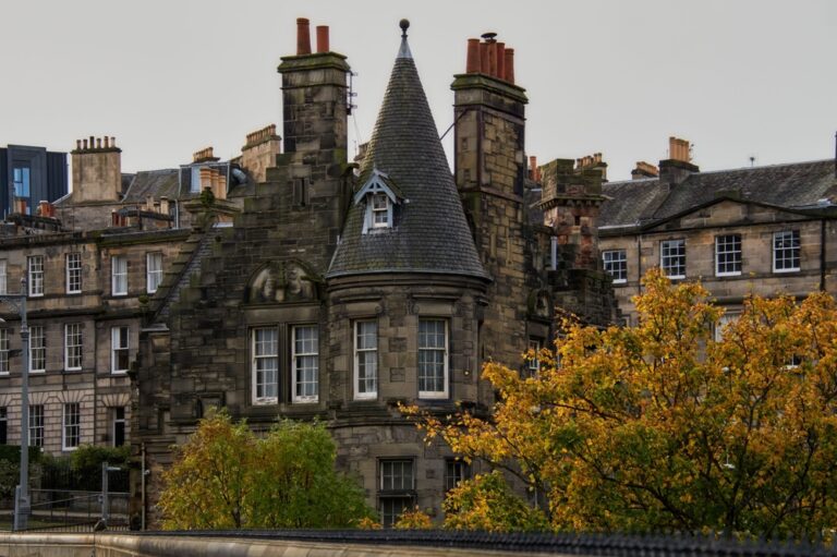 Historic stone building with a conical roof surrounded by autumn trees in Edinburgh, showcasing classic architecture.
