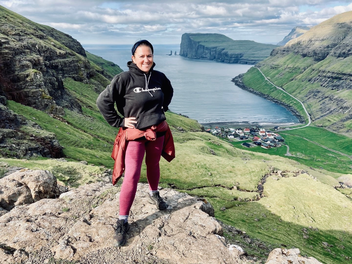 Kinga Eysturland na szlaku górskim Saksun – Tjørnuvík na wyspie Streymoy, z widokiem na ocean i wioskę.