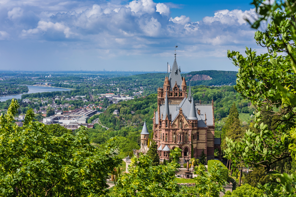 Zamek Drachenburg w Niemczech z widokiem na dolinę Renu i góry Siebengebirge w słoneczny dzień.